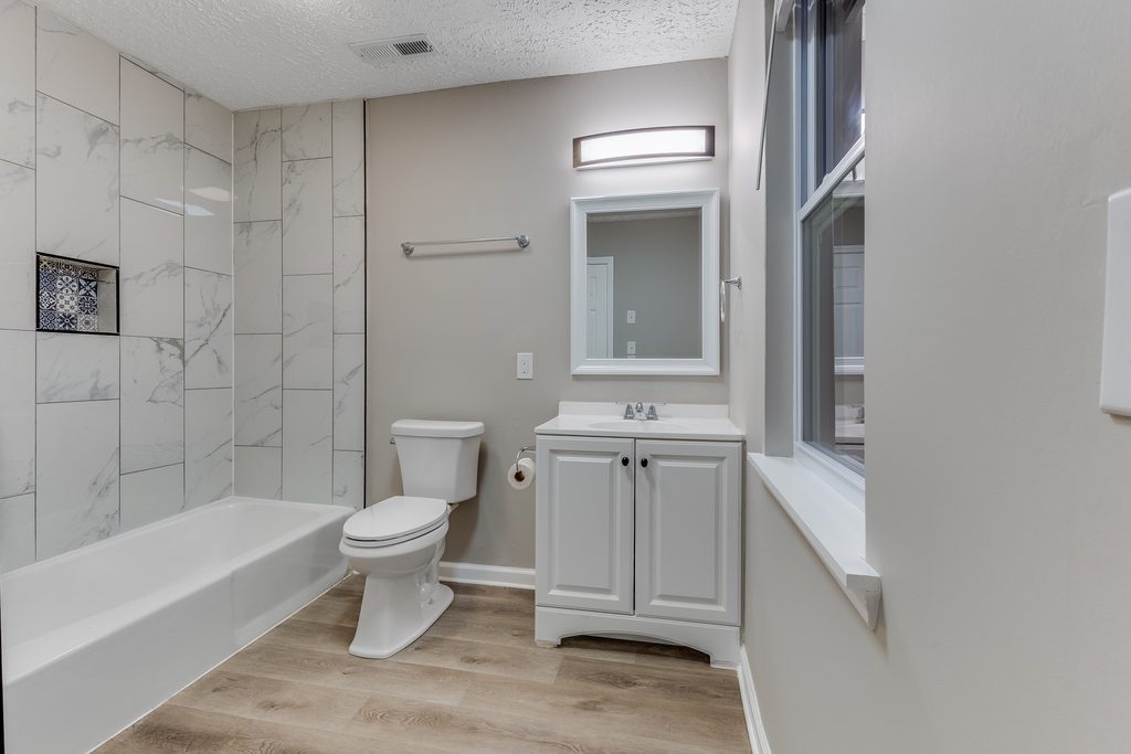 Renovated full bathroom in Chattanooga — marble-look tile shower surround and new vanity